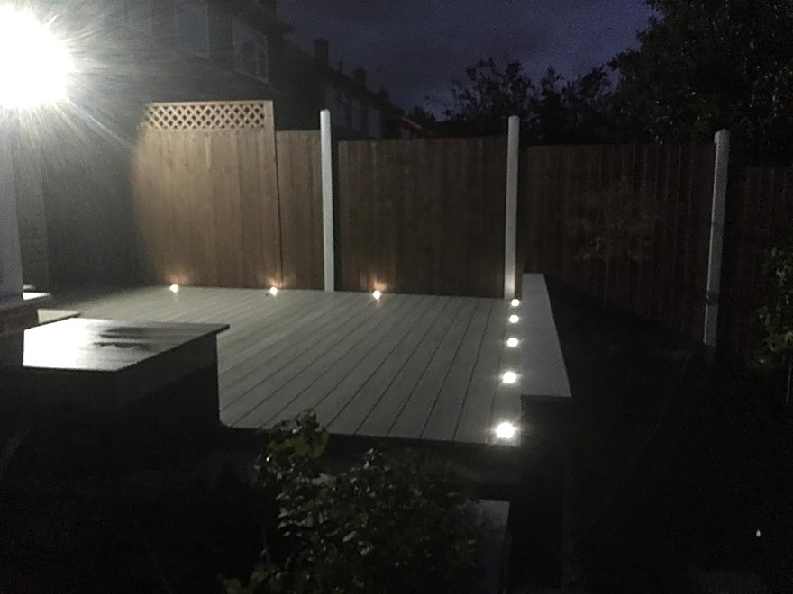 Decking lit at night with recessed deck lights and post lighting